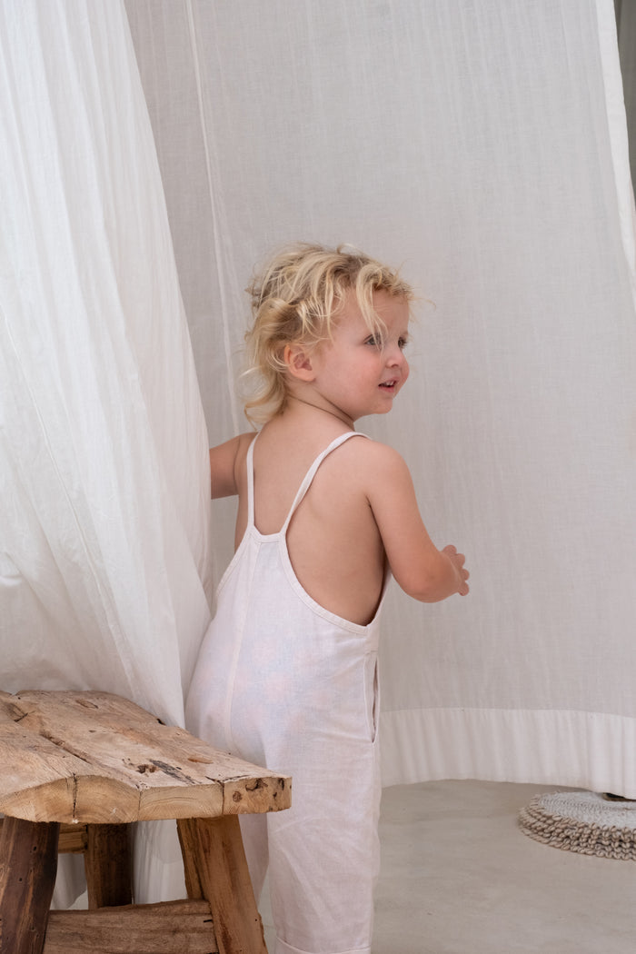 A child with blond hair wearing a white overall