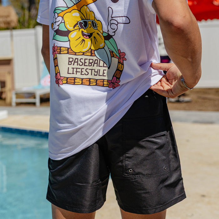 Close-up of BL101 black swim trunks lifted poolside to show the gray built-in compression liner and BL101 logo on the front pocket.