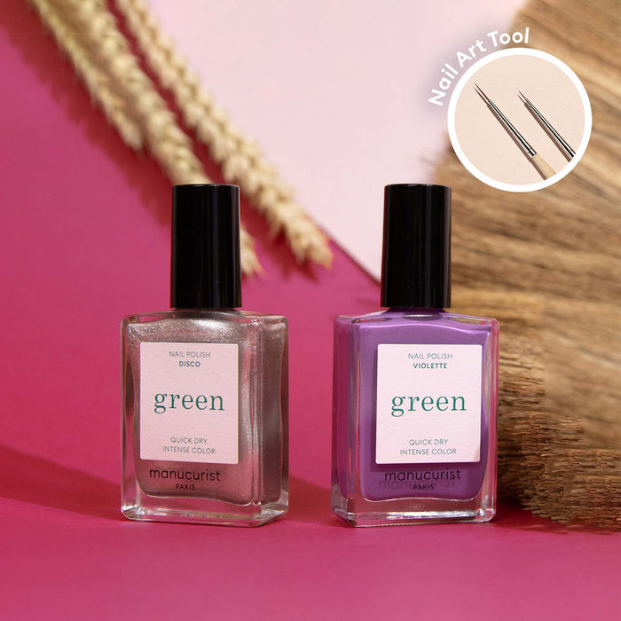 Two bottles from Manucurist's Shiny Summer collection—shimmery pink and purple—rest on a pink surface with dried plants behind. A circular inset shows two Nail Art Brushes, ideal for creating Arty Shiny Summer nail art.