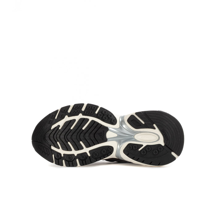 Youth adidas sneakers outsole view with textured rubber tread on black-and-cream soles.