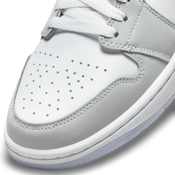 Front toe of white and light gray mid-top sneakers with perforated detailing