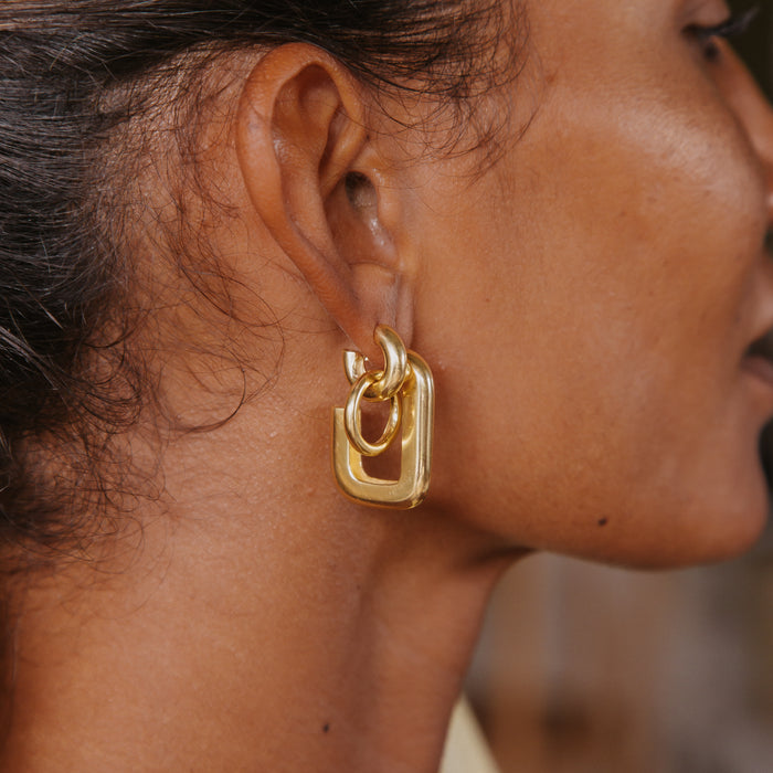 A close-up side view of a womans ear with two earrings in her ear