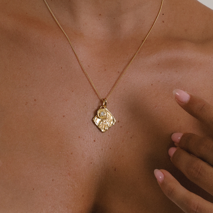 Gold necklace with a pendant on a person's neck