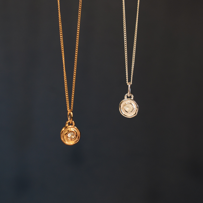 Two gold necklaces with pendants on a dark background