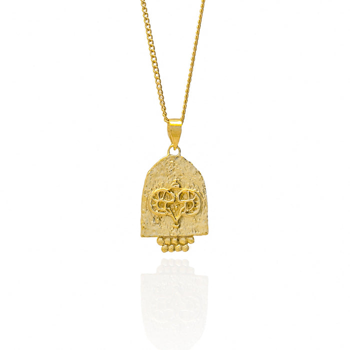 A gold pendant featuring an engraved design on a white background.