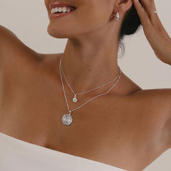 Close-up of a woman wearing a sparkling peridot birthstone necklace with a timeless design