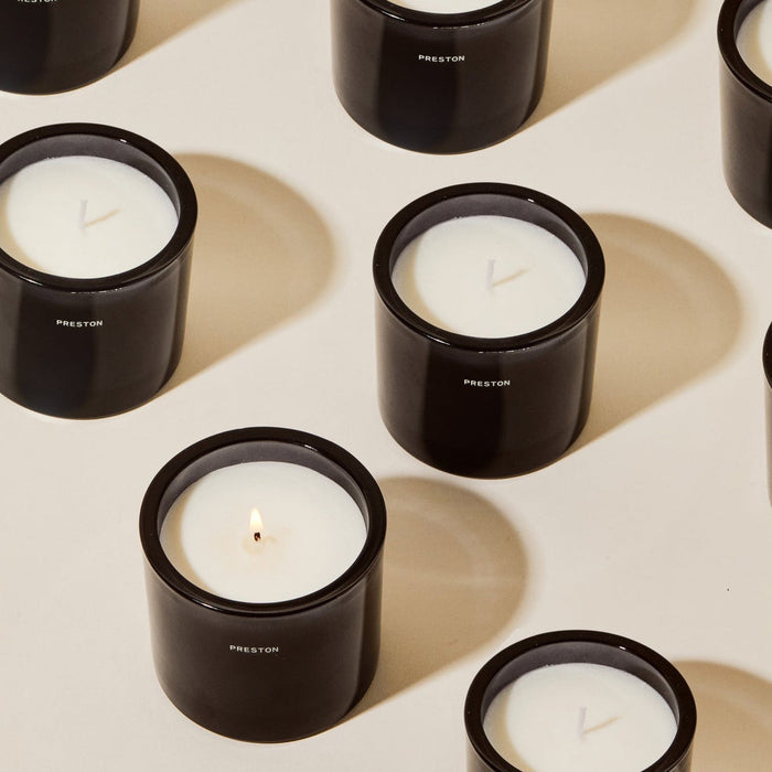 Set of black glass jar candles with white wax and one lit wick