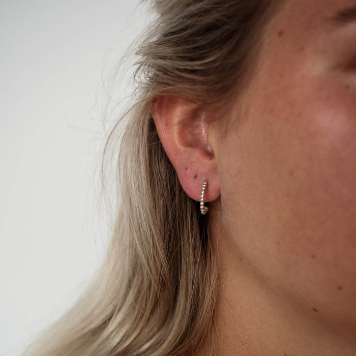 A woman with blonde hair wearing a small silver earring