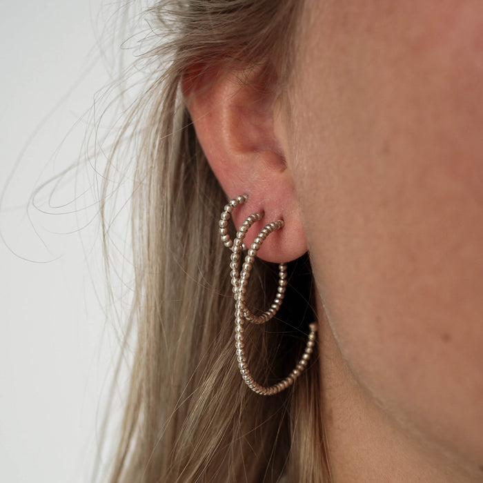 A woman with blonde hair wearing three the same earrings in different sizes