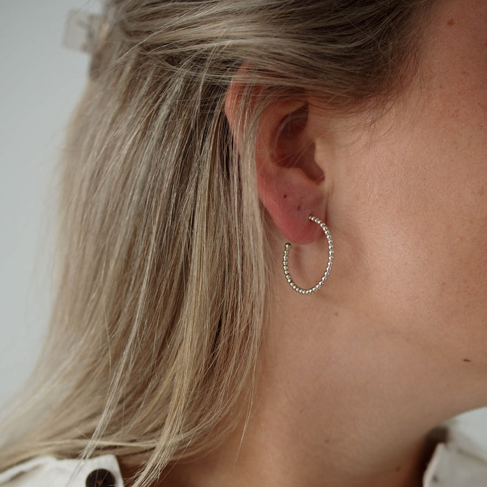 Side view of a woman with blonde hair wearing a small silver earring