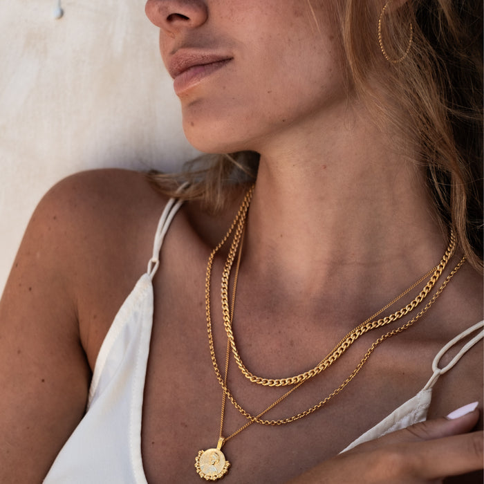 Close up of a woman's breast and neck  with multiple golden necklaces