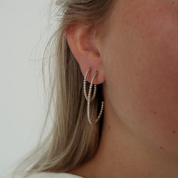 A woman with blonde hair wearing two the same earrings in different sizes