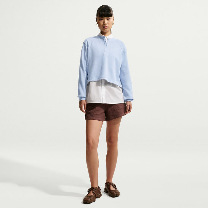 Women’s light blue long-sleeve henley knit top worn over a white layer and shorts