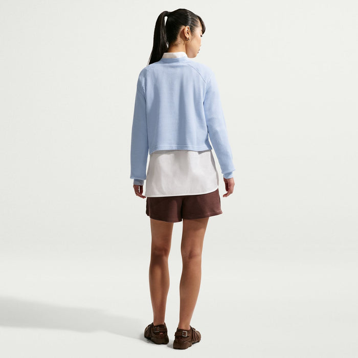 Women’s light blue long-sleeve knit henley top, back view over white layer