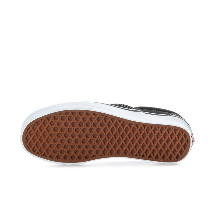 Black slip-on sneakers showing textured gum outsole with white edge trim