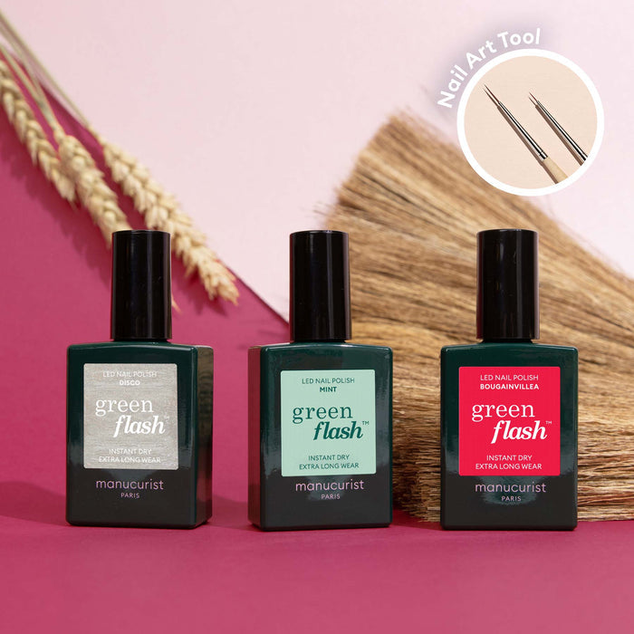 Three bottles of Manucurist Coral Reef polish are displayed on a pink surface, with a Nail Art Brush in an inset—ideal for creating Coral Reef nail art. Dried plants appear in the background.