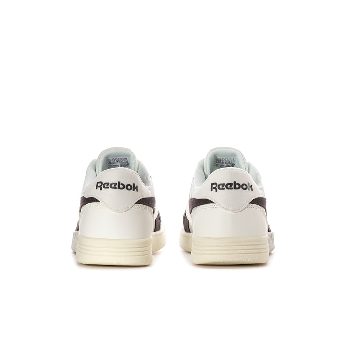 Men's white sneakers with black heel details, Reebok logo, and cream rubber sole