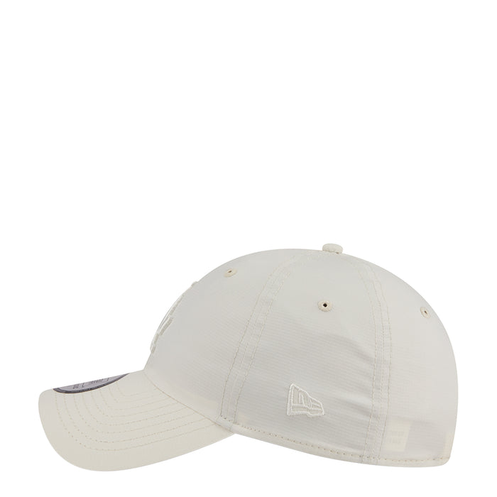 Cream strapback baseball cap with small front emblem and curved brim