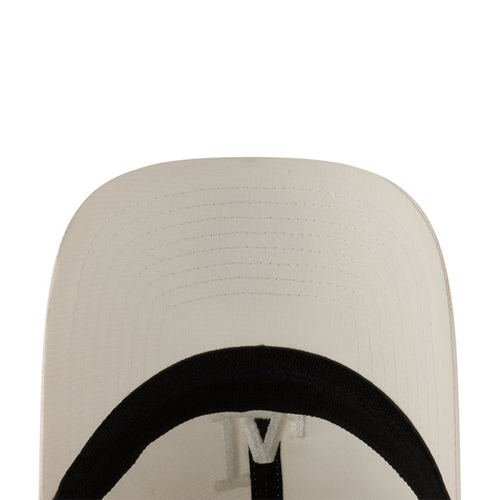 Cream cap interior close-up with black lining and adjustable strap hardware