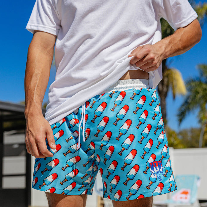 Close-up of BL101 popsicle bat print swim trunks showing the all-over red, white, and blue pattern and BL101 logo on the left leg.