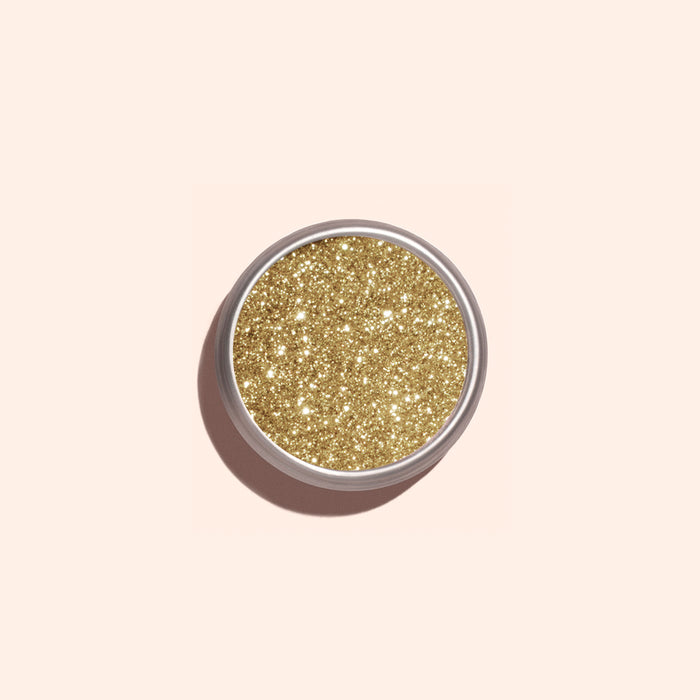 A round Manucurist Golden Chrome Powder container, viewed from above on a pale beige background, ideal for achieving a dazzling chrome finish.