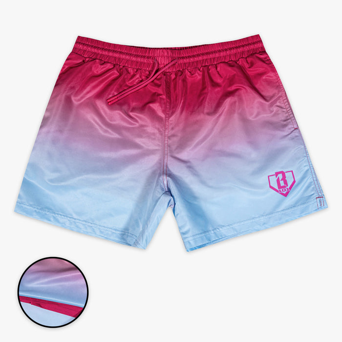 Flat lay of BL101 pink to blue ombre swim trunks on a white background with an inset detail showing the pink mesh liner.