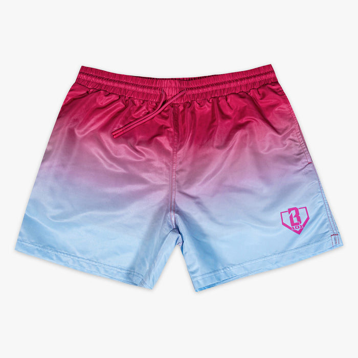 Front flat lay of BL101 pink to blue ombre swim trunks with pink drawstring waistband and pink BL101 home plate logo on the left leg.