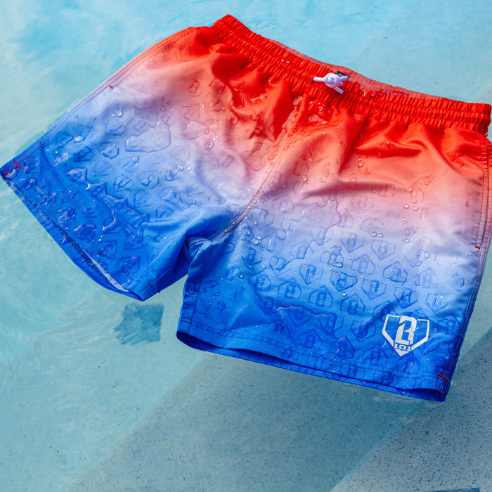 BL101 red to blue ombre swim trunks laid on a pool surface, wet and showing an all-over embossed BL101 logo pattern.