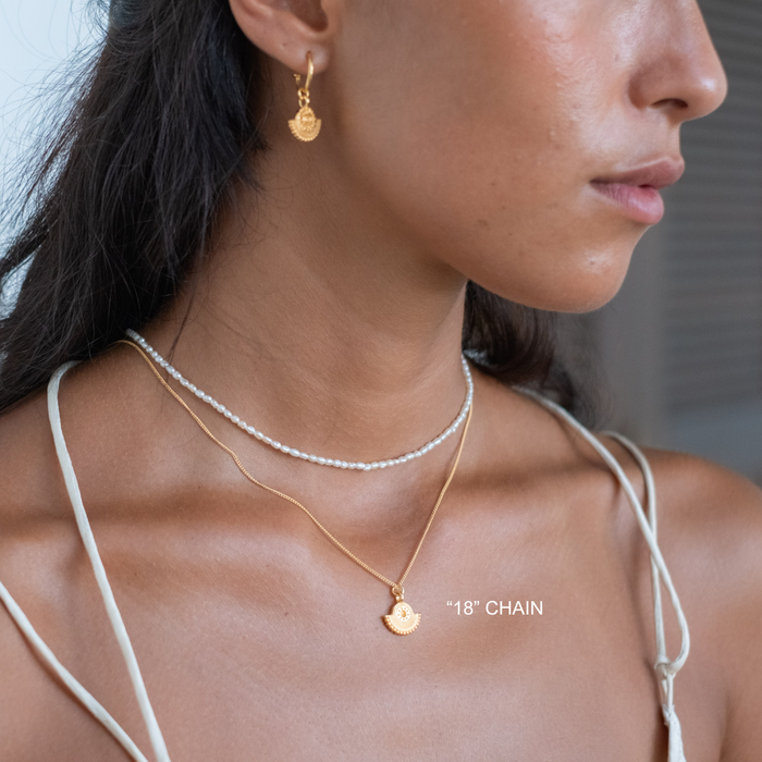 Close-up of a person wearing gold necklaces and earrings with '18' chain text.