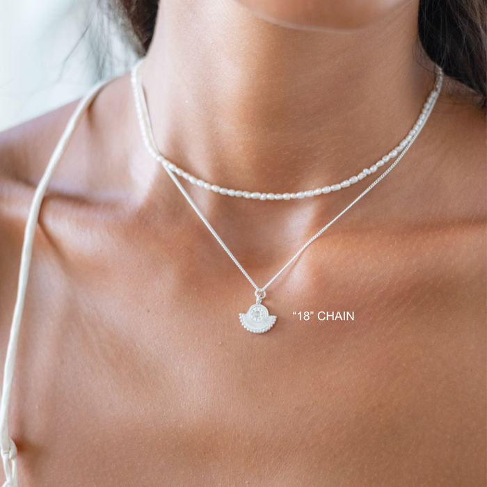 Silver necklace with a pendant on a person's neck