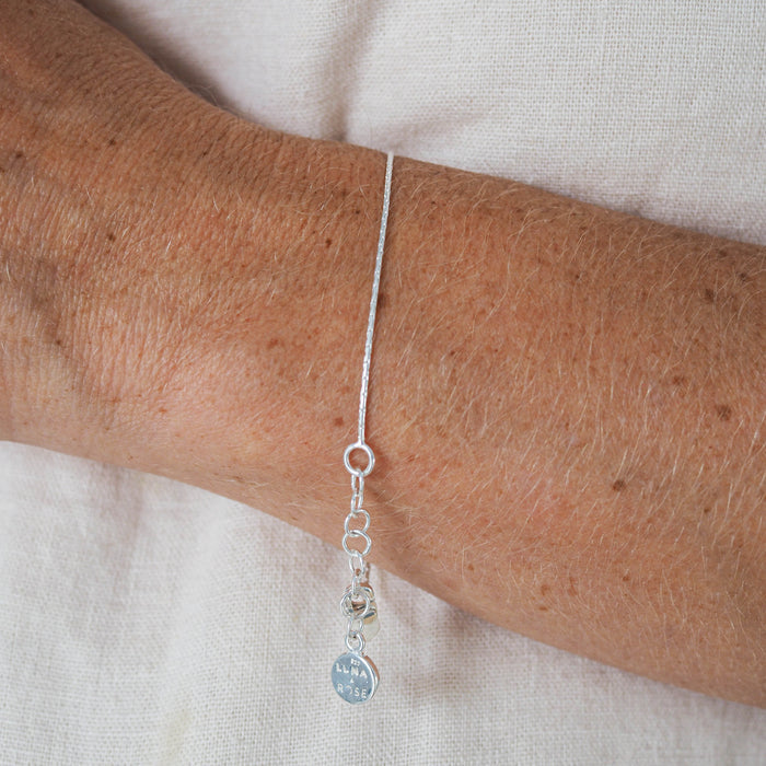 Close-up of a woman wearing a silver bracelet, paired with a white blouse