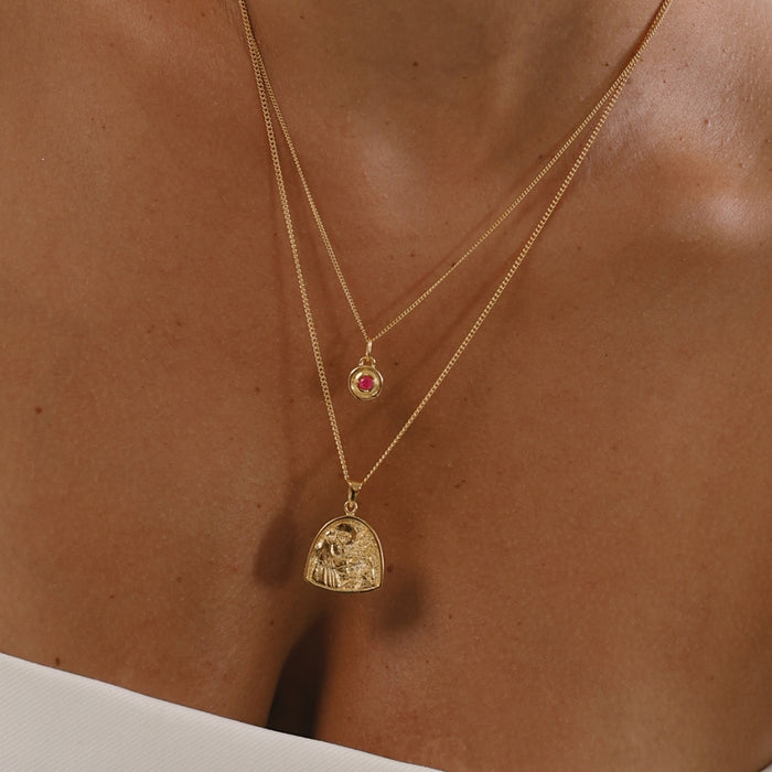 Gold necklace with a heart-shaped pendant on a person's neck