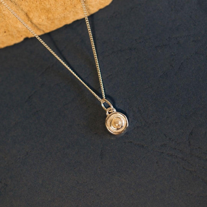 Gold necklace with a pendant on a dark textured surface