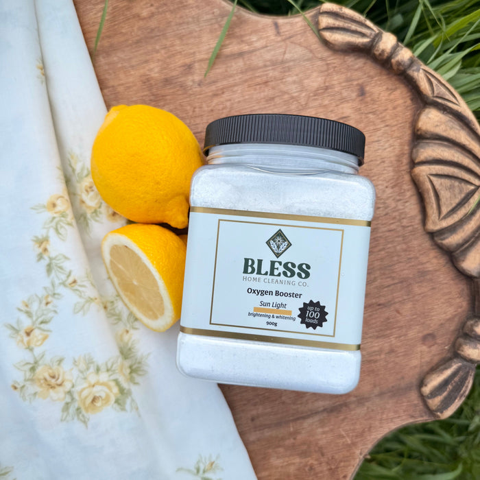 Container of 'BLESS' product on a wooden board with lemons and a cloth in the background