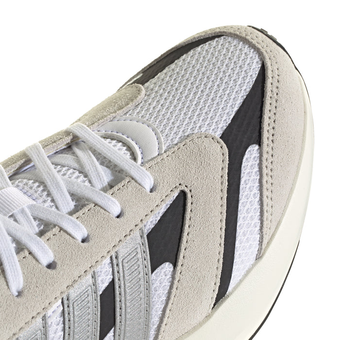 Close-up of women's sneaker with suede beige paneling, white laces, and textured mesh