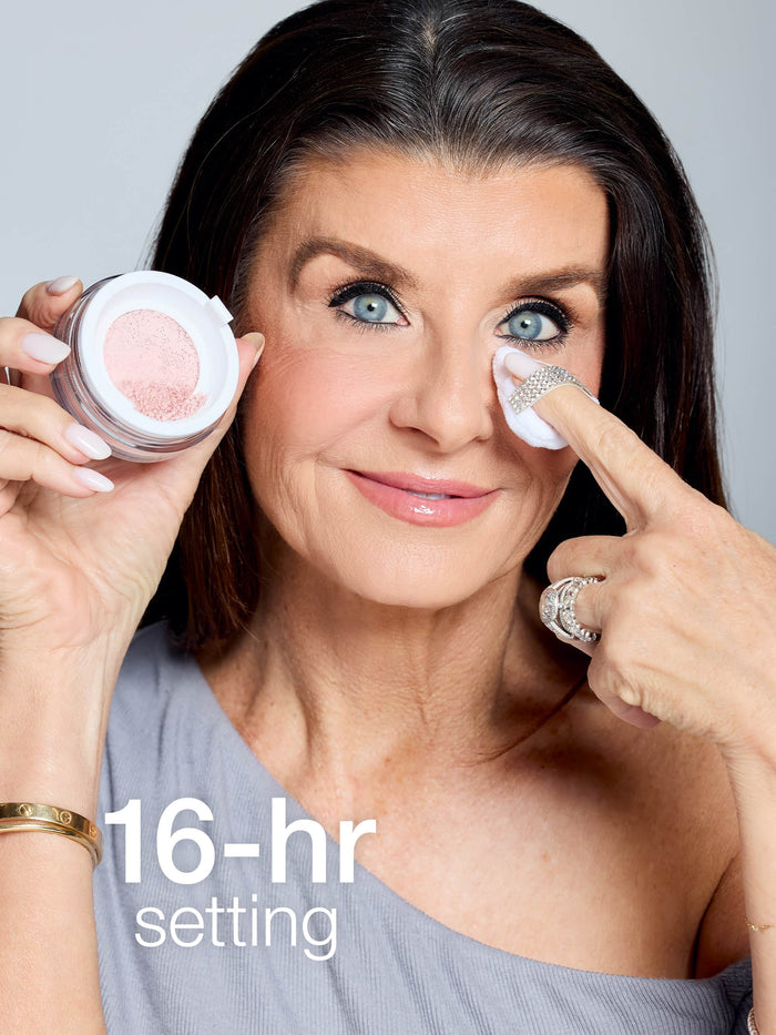 A woman applies makeup under one eye, holding Tarte Cosmetics powder and wearing a gray top. Text reads 16-hr setting.