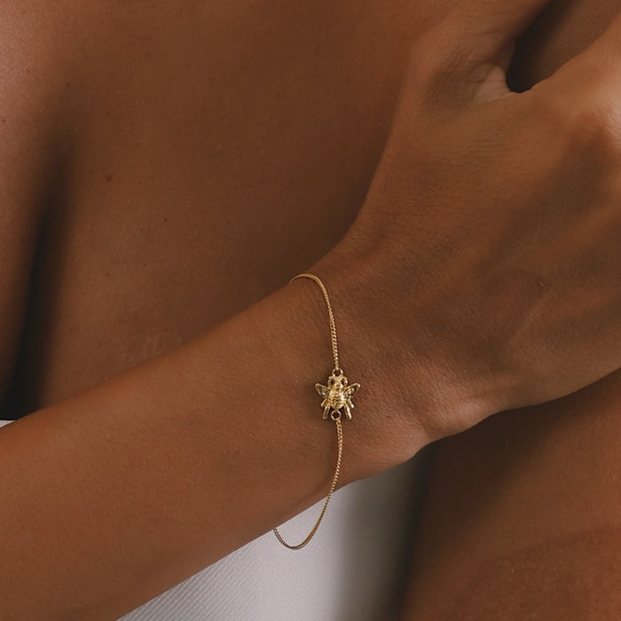 Gold jewelry set including necklace, bracelet, and ring on a person against a neutral background