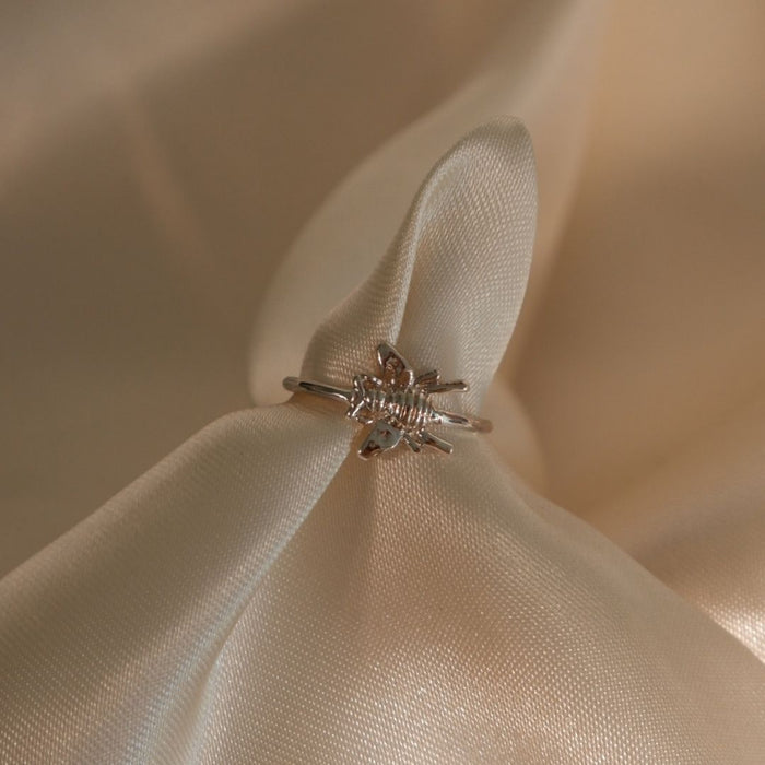 Silver ring with a detailed design on a beige fabric background