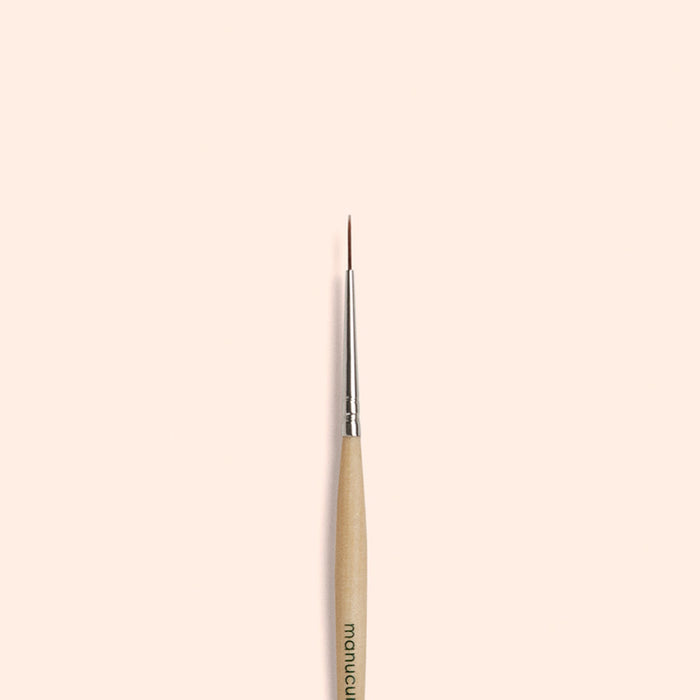 The Manucurist Liner Brush, featuring vegan synthetic bristles and a fine tip, is vertically centered on a simple light beige background.