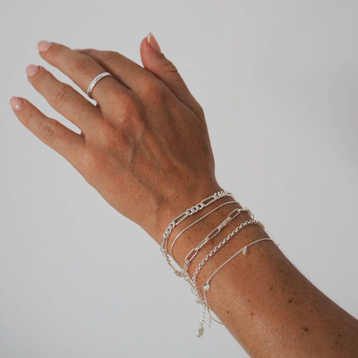 Close-up of a woman's wrist wearing a multiple silver chain bracelets
