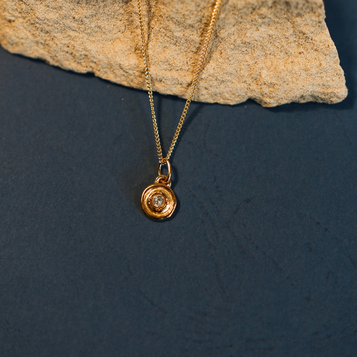 Gold necklace with a pendant on a dark surface