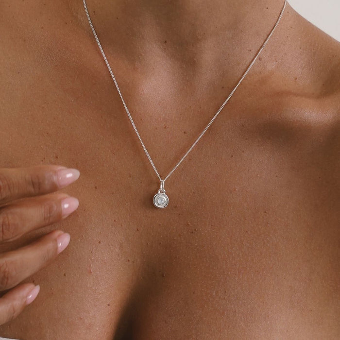 Silver necklace with a pendant on a person's neck
