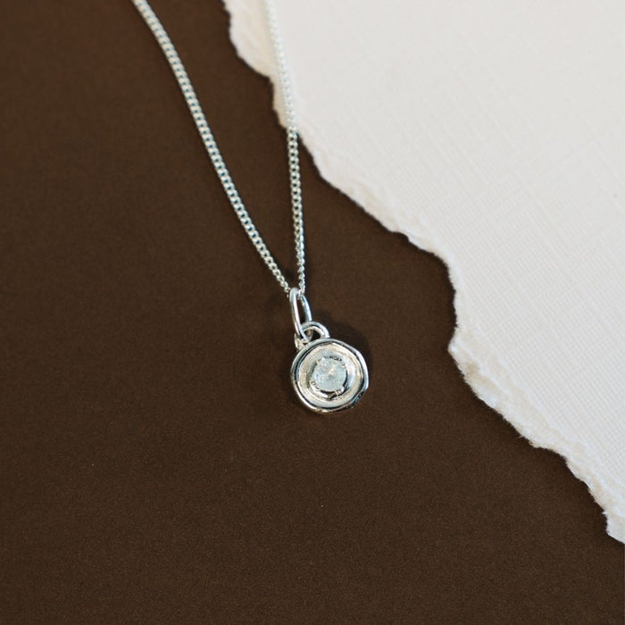 Silver necklace with a pendant on a brown and beige background