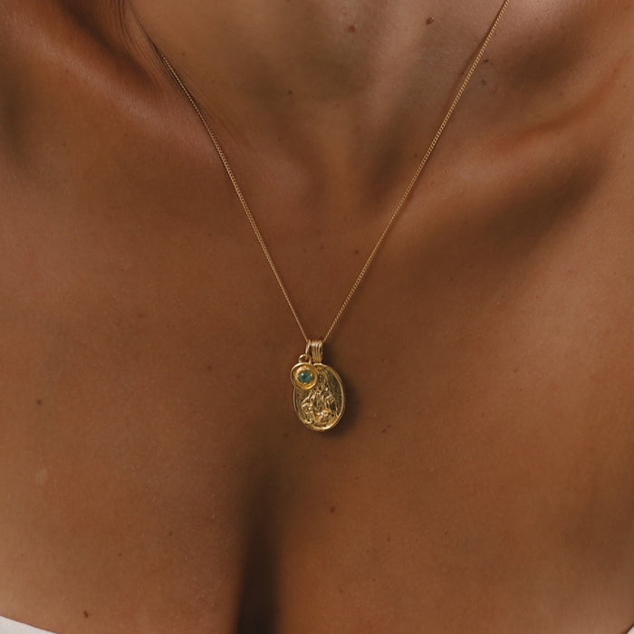 Gold necklace with a pendant on a person's neck
