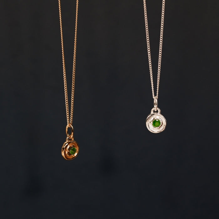 Two necklaces with green gemstones on a black background