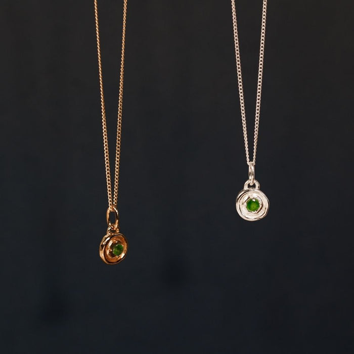 Two necklaces with green gemstones on a dark background