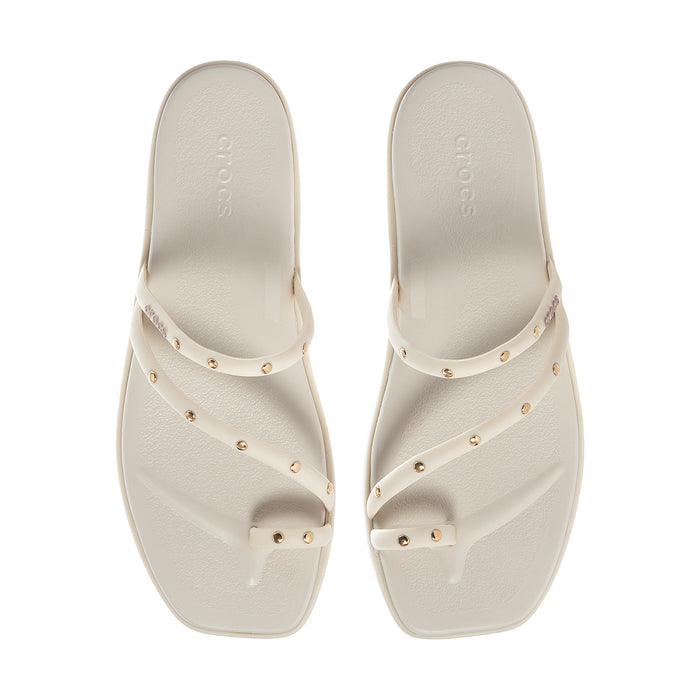 Pair of women’s light toe-loop sandals with studded straps on the footbed
