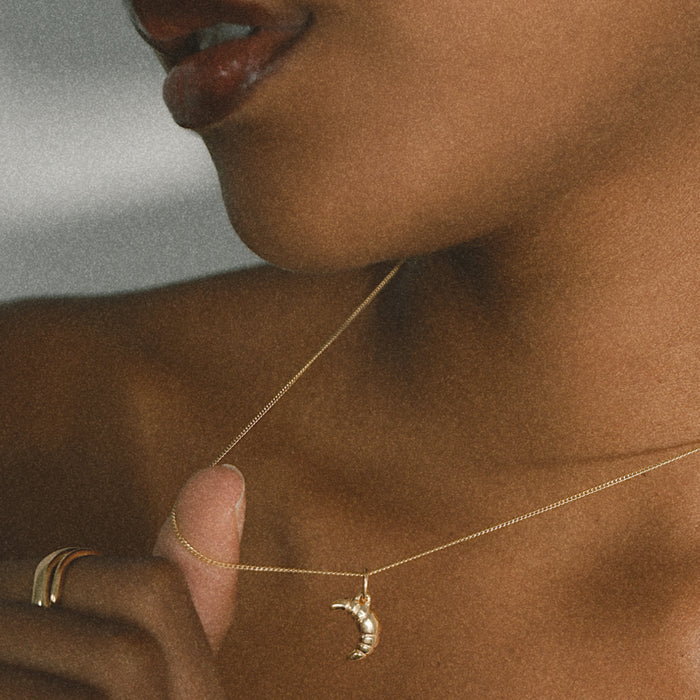 Mini Croissant Necklace in Gold from the ACME x Luna & Rose collection, a dainty croissant-shaped pendant for an elegant and playful touch.