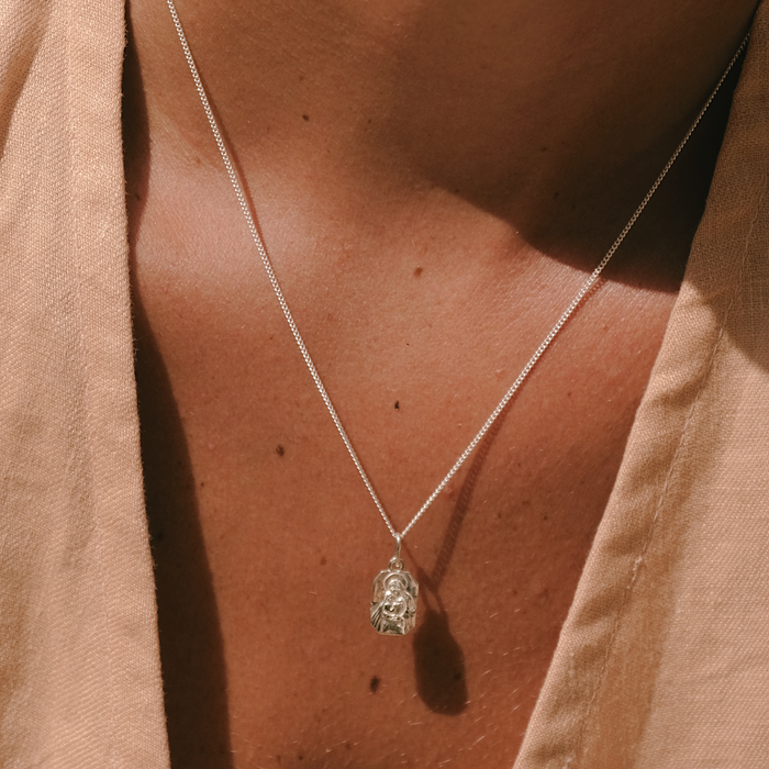 Necklace with a pendant worn by a person, with a neutral background
