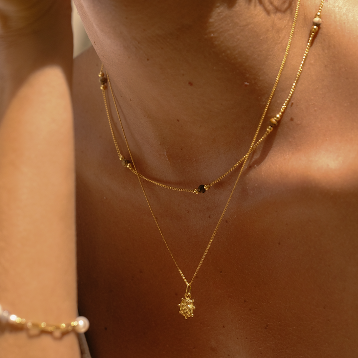 Close-up of a person wearing gold necklaces with a soft background